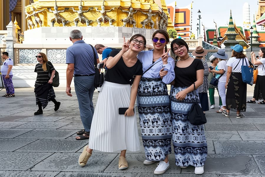 Turisti che rispettano il codice di abbigliamento in un magnifico tempio buddista in Thailandia.